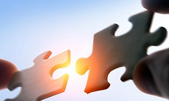 Two pieces of a jigsaw fitting together, symbolising a merger of two companies